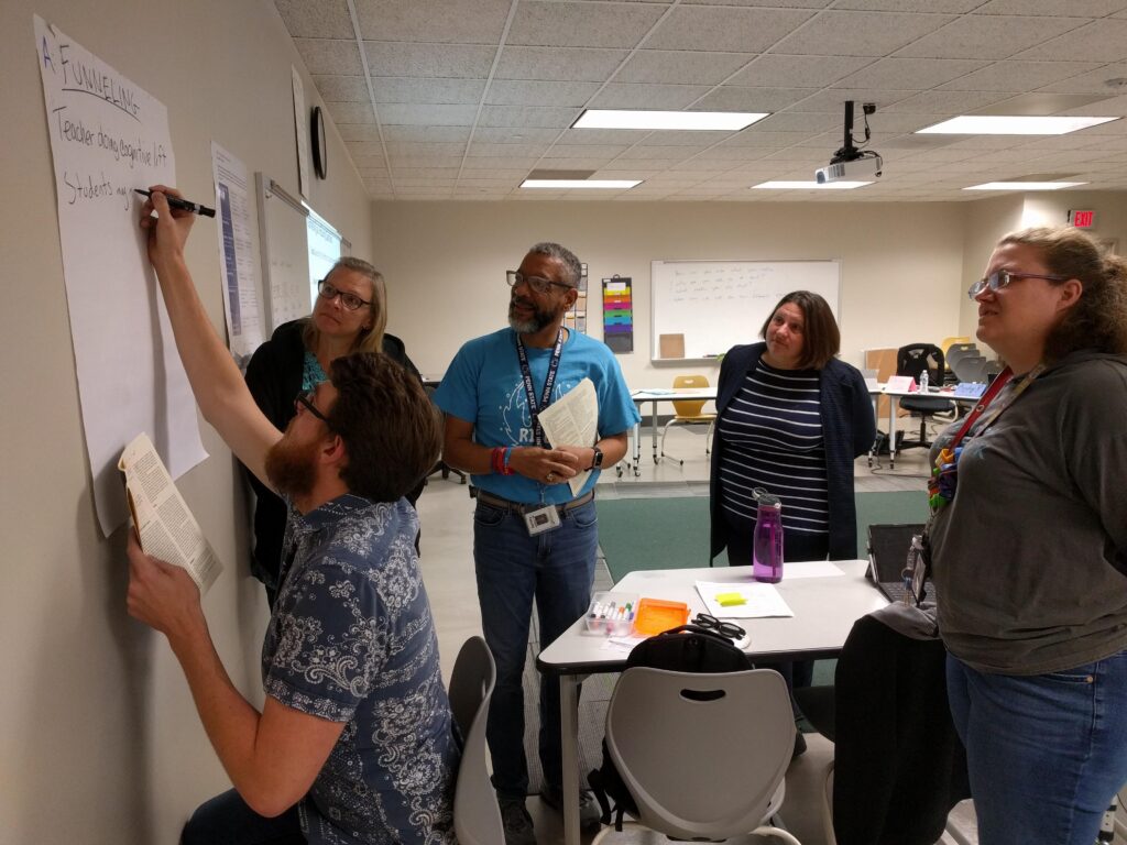 Teachers watching another teacher writing on a white board