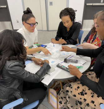 A group of teachers around a circular table discussing paper work