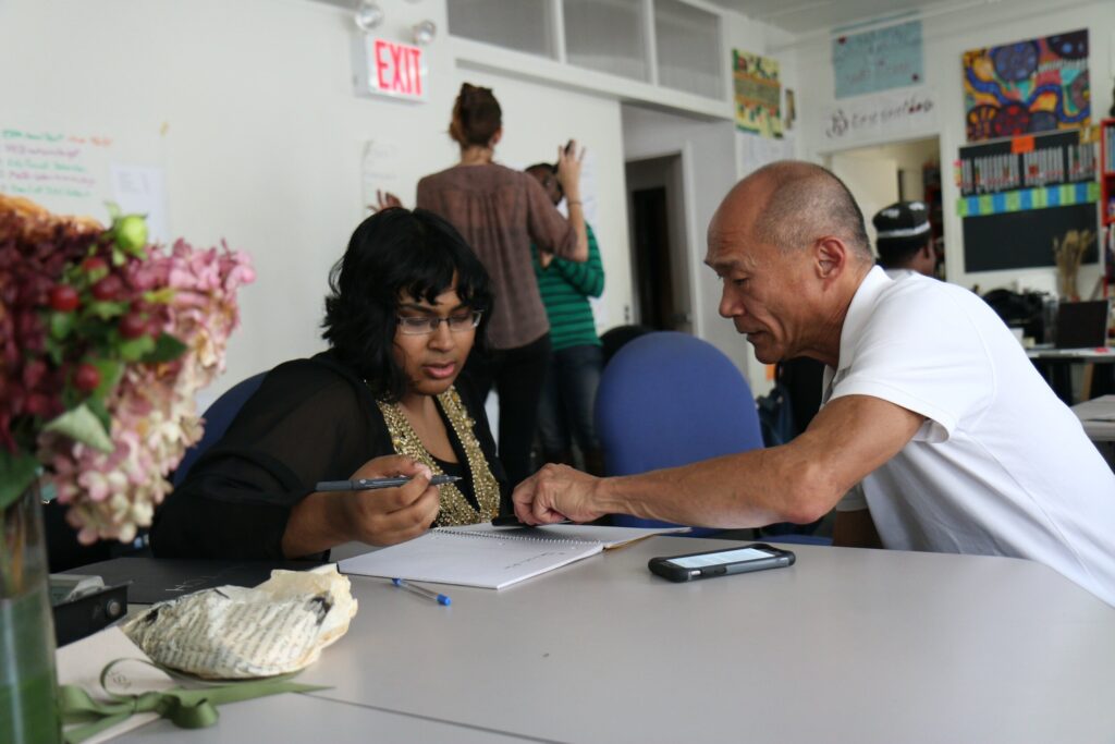 A woman and an older man at a table discussing some paper work